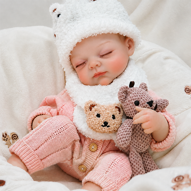 Close-up of a realistic reborn doll with closed eyes, softly blushed cheeks, natural lips, detailed hands, and delicate baby-like facial features.