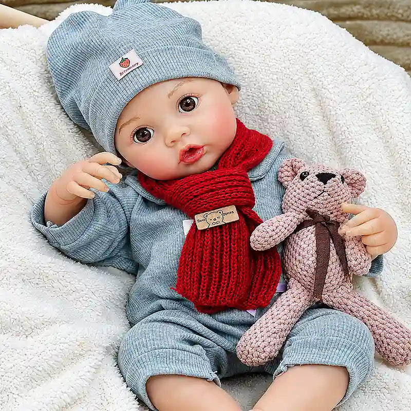 Adorable reborn baby holding a pink teddy bear on a fluffy blanket, perfect for storytime, pretend play, Christmas photos, and cozy nursery displays.