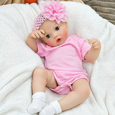 Lifelike feeding baby doll with carefully painted facial details, expressive eyes, soft rosy cheeks, tiny hands, and a textured flower headband.