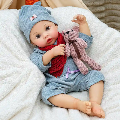 Clara features a charming bear-ear hat, textured blue outfit, bright red scarf, natural rosy coloring, expressive eyes, and carefully crafted baby details.