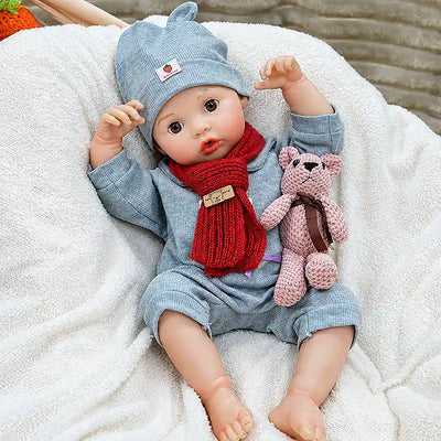 Realistic reborn baby doll Clara  with a sweet open-mouth expression, delicate eyelashes, soft-looking skin, detailed fingers, and warm seasonal clothing.