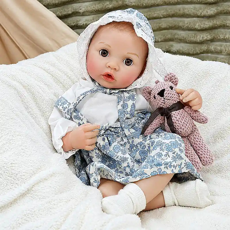 Ellis relaxes on a soft blanket with a teddy bear, ready for bottle time, bedtime stories, pretend parenting, and warm family moments.