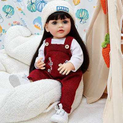 Long-haired reborn doll Charlotte with a gentle expression, handcrafted knitwear, floral details, and a charming seated pose, perfect for display, photography, birthdays, and Christmas gifts.