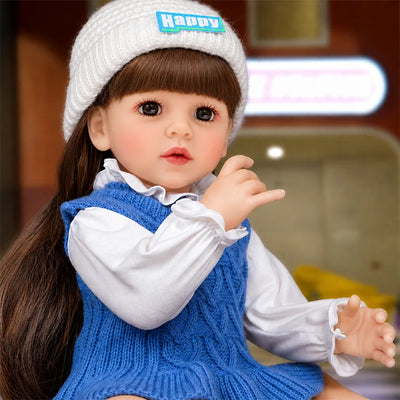 Realistic reborn doll featuring bright brown eyes, soft blushed cheeks, delicate pink lips, detailed fingers, and long dark hair.