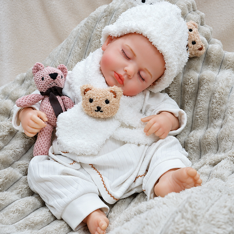 Lifelike Ollie doll featuring carefully painted facial details, closed sleeping eyes, a gentle expression, tiny feet, and textured plush clothing with a bear hat.