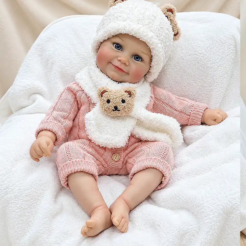 Reborn baby doll in a cozy bear outfit, seated on a soft blanket for a gift photo.