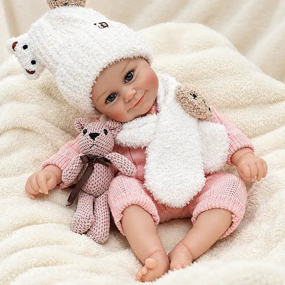Reborn baby doll wearing a textured pink knit romper and a white bear hat with a matching scarf.