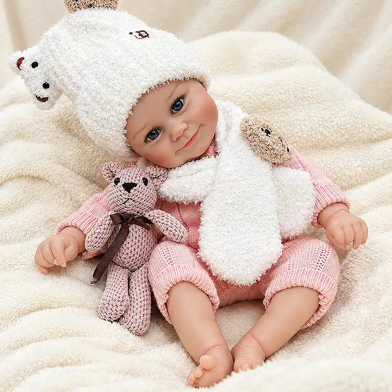 Reborn baby doll wearing a textured pink knit romper and a white bear hat with a matching scarf.