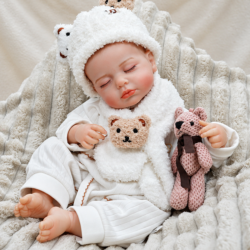 Peaceful reborn baby doll Ollie with delicate eyelashes, soft pink lips, natural rosy cheeks, detailed fingers, and a cozy bear-themed outfit for bedtime scenes.