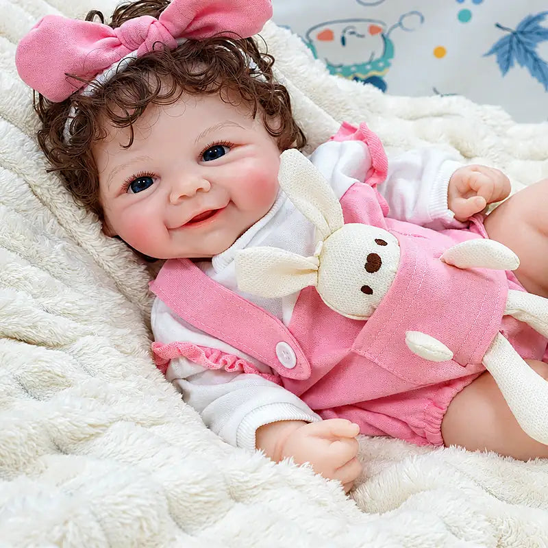 Adorable Layla wears a pink outfit with a matching bow and enjoys cuddles, tea parties, dress-up games, and nurturing role play.