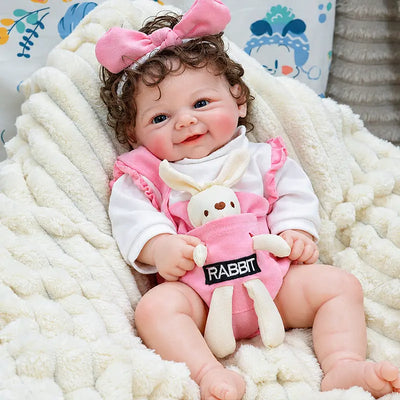 Sweet silicone baby Layla with glossy lips, gentle eyes, natural rosy coloring, curled brown hair, and carefully crafted lifelike details for display or gifting.