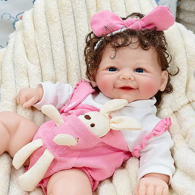 Lifelike silicone reborn baby Layla with soft-looking limbs, expressive eyes, delicate fingers, curly brown hair, and a cozy pink outfit for cuddles and companionship.