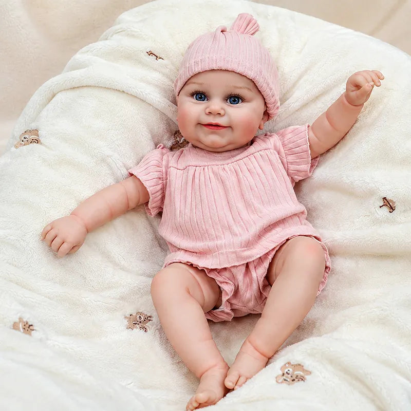 Smiling Eliza reborn baby doll with a tilted head, blue eyes, chubby cheeks, and playful pink ruffles.