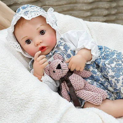 Bottle-feeding Ellis brings everyday caregiving to life with realistic baby details, a cute seated pose, delicate fingers, and a playful teddy bear companion.