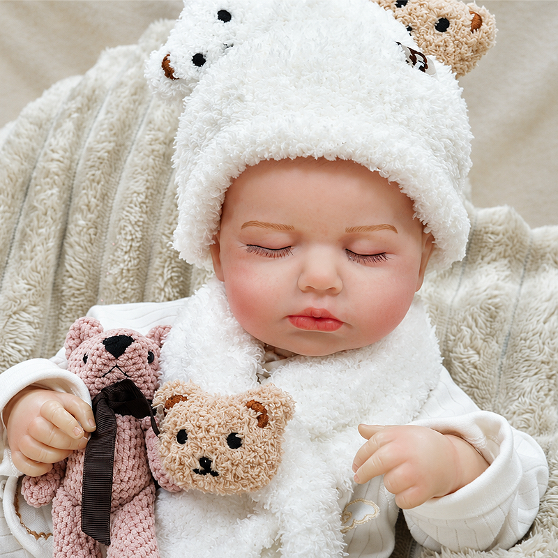 Sweet Ollie wears a soft white bear romper and cuddles a teddy friend, making him ideal for nurturing role play, bedtime routines, collectors, and gift giving.