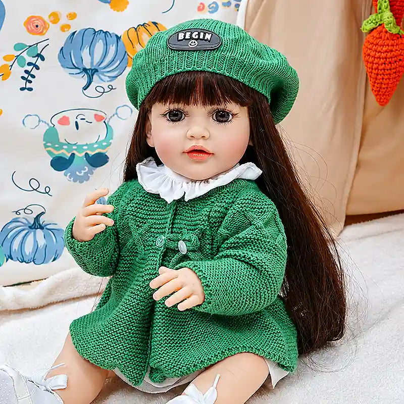 A sweet reborn girl doll Amelia sitting on a soft blanket in a cozy play tent, dressed in textured green knitwear with tiny white shoes, ready for storytime adventures.