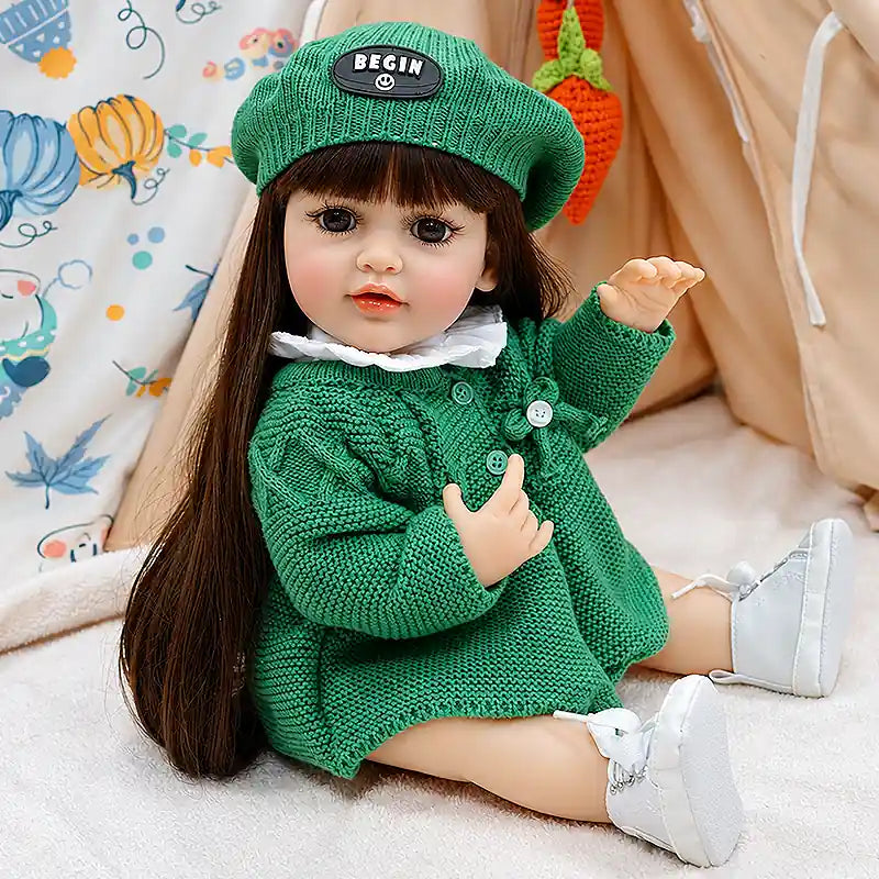 Realistic Amelia doll with a gentle expression, soft-looking vinyl or silicone-style details, a handmade green outfit, and a playful pose for pretend caregiving and companionship.