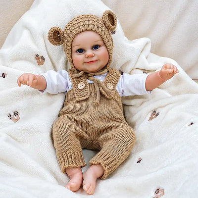 Soft vinyl reborn doll in textured caramel knitwear, with lifelike facial details.