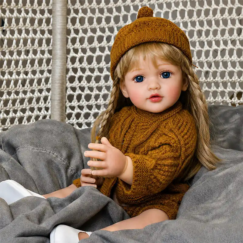 Adorable reborn doll with sparkling blue eyes, long blonde hair, rosy skin tones, and a cozy autumn-inspired outfit.
