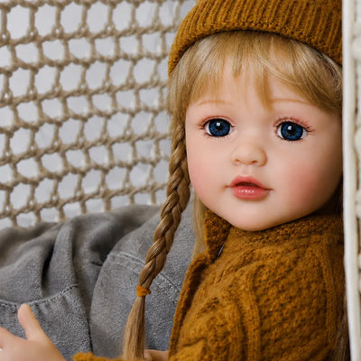 Realistic baby doll in a mustard knit sweater and matching beanie, ready for cozy autumn playtime and family-inspired pretend adventures.