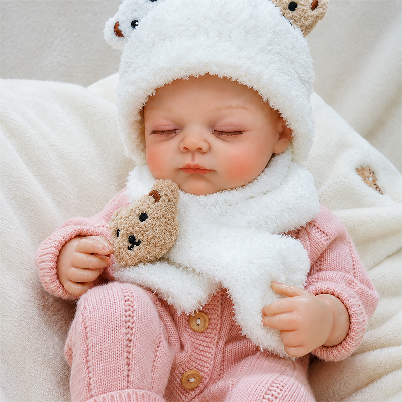 Realistic reborn baby doll in a soft pink knitted outfit, featuring lifelike facial details, natural blush, and a peaceful sleeping expression.