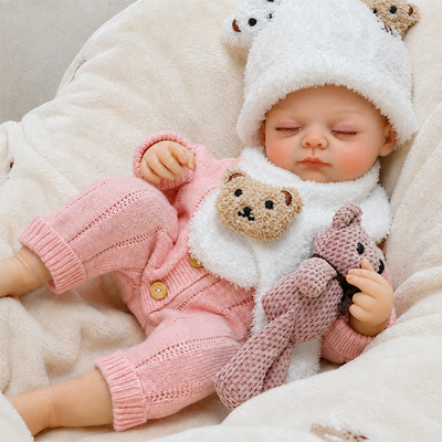 Cozy reborn baby doll resting on a soft blanket with a plush bunny, ideal for pretend play, cuddling, nursery displays, and photography.
