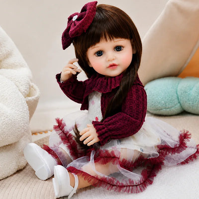 Lifelike reborn doll dressed in a burgundy outfit