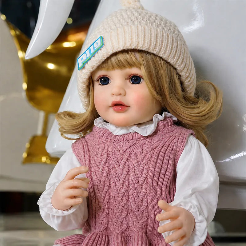 Realistic reborn doll dressed in a pink knitted outfit and cream beanie, perfect for pretend play, gifting, and doll collection displays.