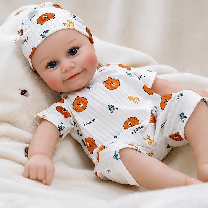Lifelike reborn baby doll with bright blue eyes, rosy cheeks, a sweet smile, and a matching teddy bear romper and hat.