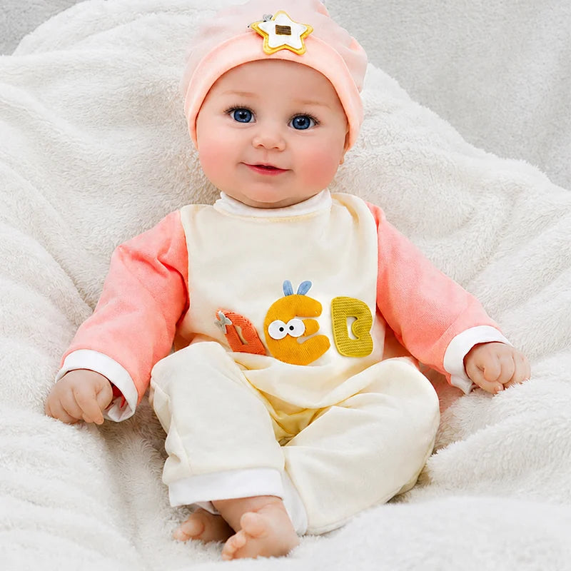 Cute reborn baby doll sitting on a cozy white blanket, perfect for nursery play, pretend parenting, cuddling, and imaginative everyday activities.