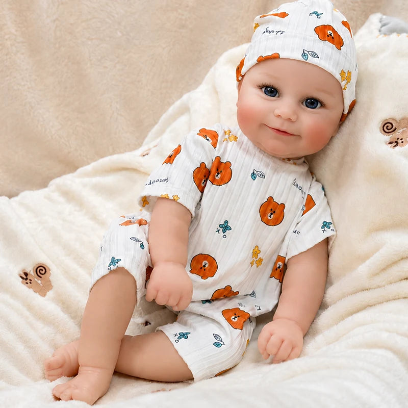 Realistic reborn baby doll featuring expressive blue eyes, naturally blushed cheeks, detailed facial features, and an adorable smiling expression.