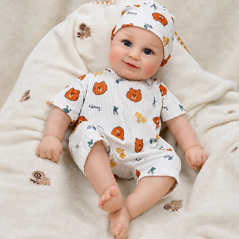 Cute reborn baby doll relaxing on a soft cream blanket, dressed in a teddy bear outfit for cozy nursery play, cuddling, and pretend parenting.