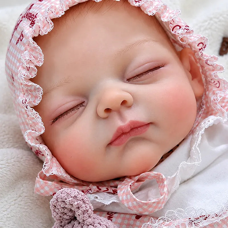 Close-up of a realistic reborn baby doll with gently closed eyes, soft pink lips, natural-looking skin tones, and finely sculpted newborn facial features