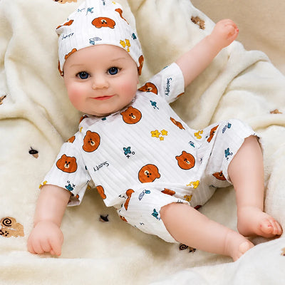Happy reborn baby doll with a cheerful smile, chubby cheeks, bright blue eyes, and a playful teddy bear outfit full of sweet personality.